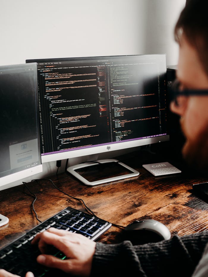 brand-01 Focused software developer at desk coding with multiple monitors in a modern workspace.