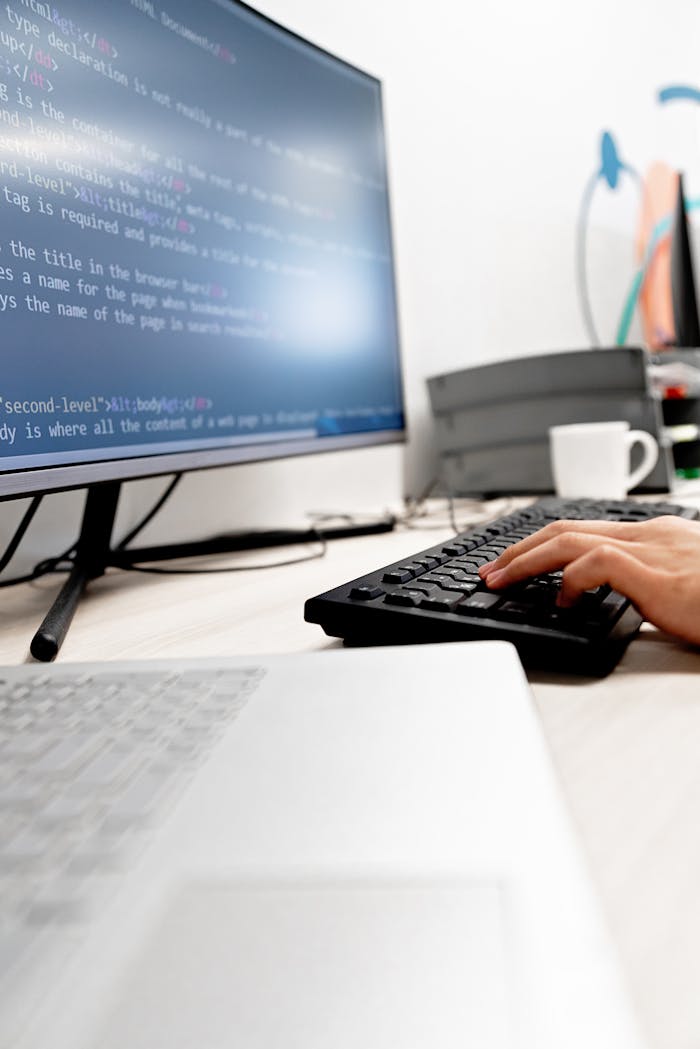 brand-03 Close-up of hands typing code on a computer monitor in an office setting.